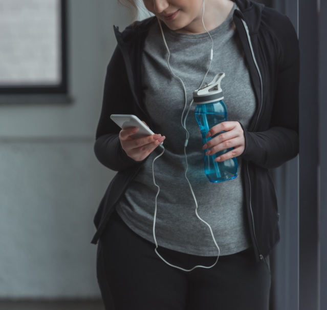 Girl in gym clothes looking at cell phone.